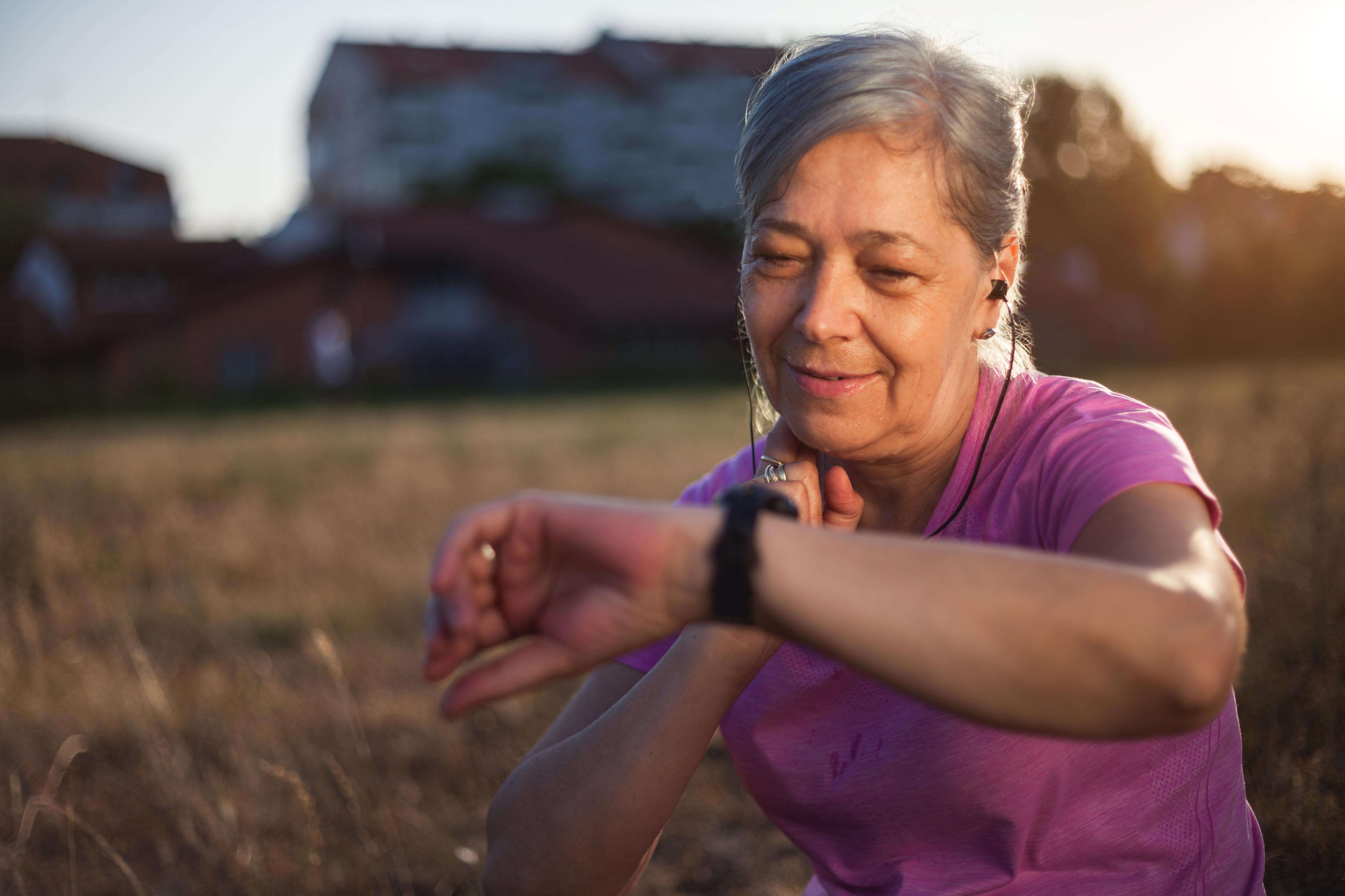 Woman exercising outdoors checks fitness tech on wrist