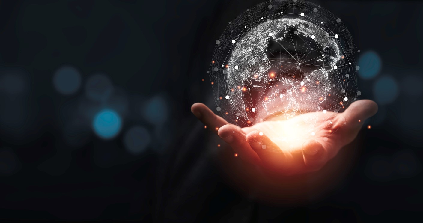 Hand is lit up in darkness and is holding a world globe
