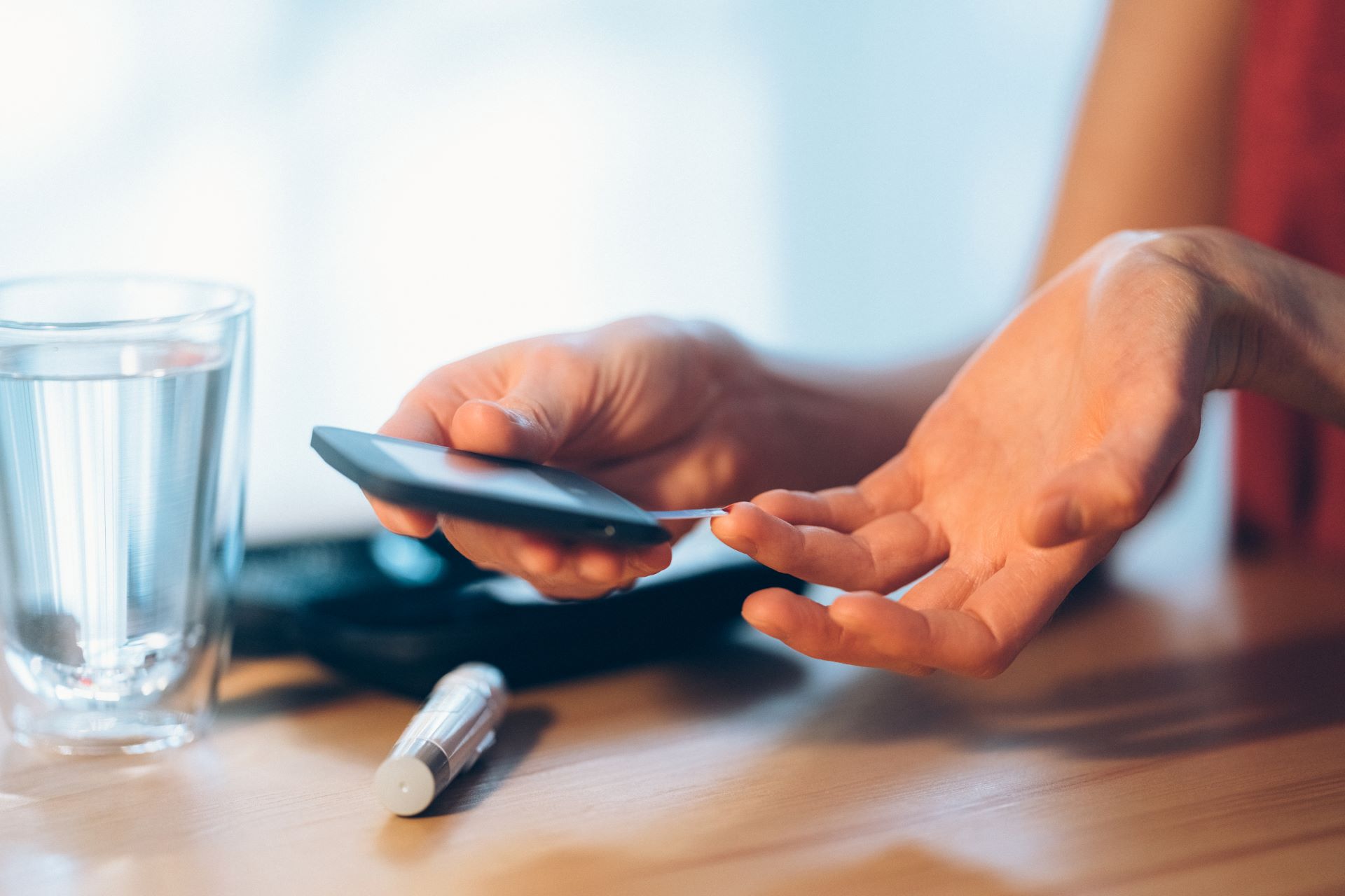 Close up of person's hands as they use diabetes monitor at home