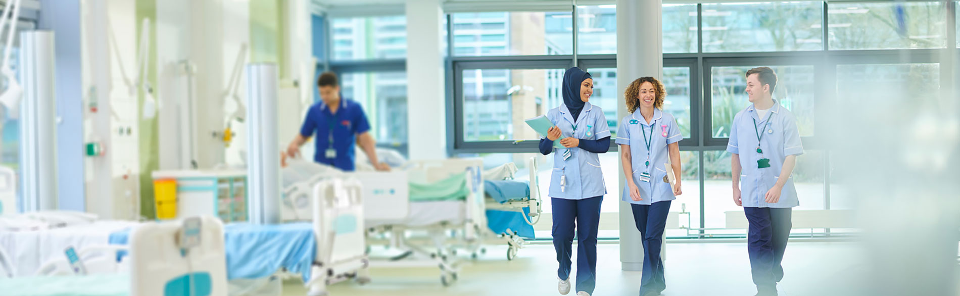 Three clinicians walking through a hospital ward
