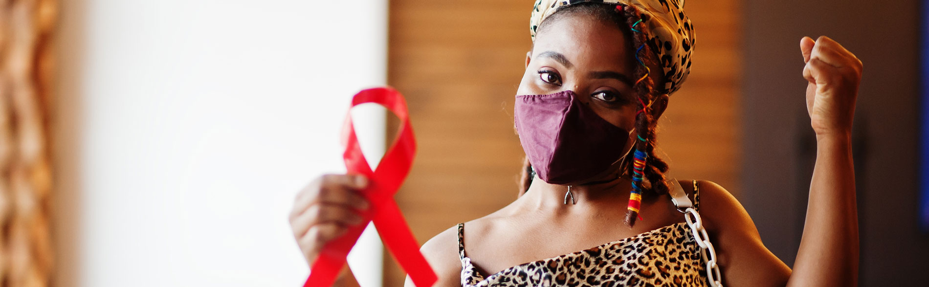 Woman holds up a red AIDS ribbon while she fights AIDS stigma discrimination