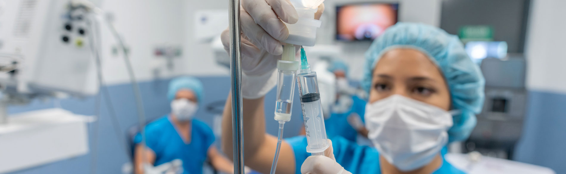 Nurse administering etomidate to an intravenous drip in a theatre setting