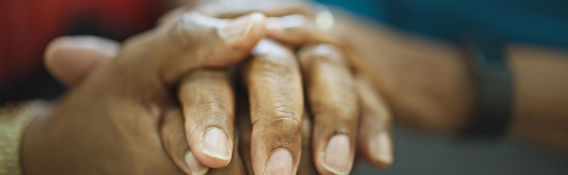 A close up of a clinician or loved one holding the hands of someone at the end of their life.