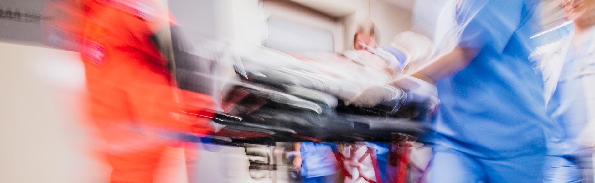 Emergency staff running a stretcher through the hospital corridor in a blur