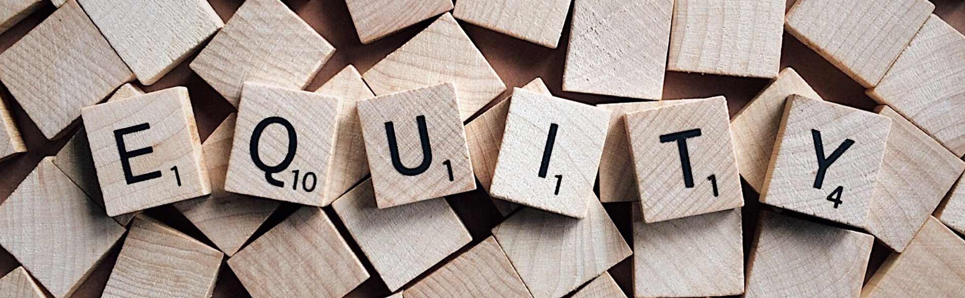 Wooden scrabble tiles spelling 'equity'.