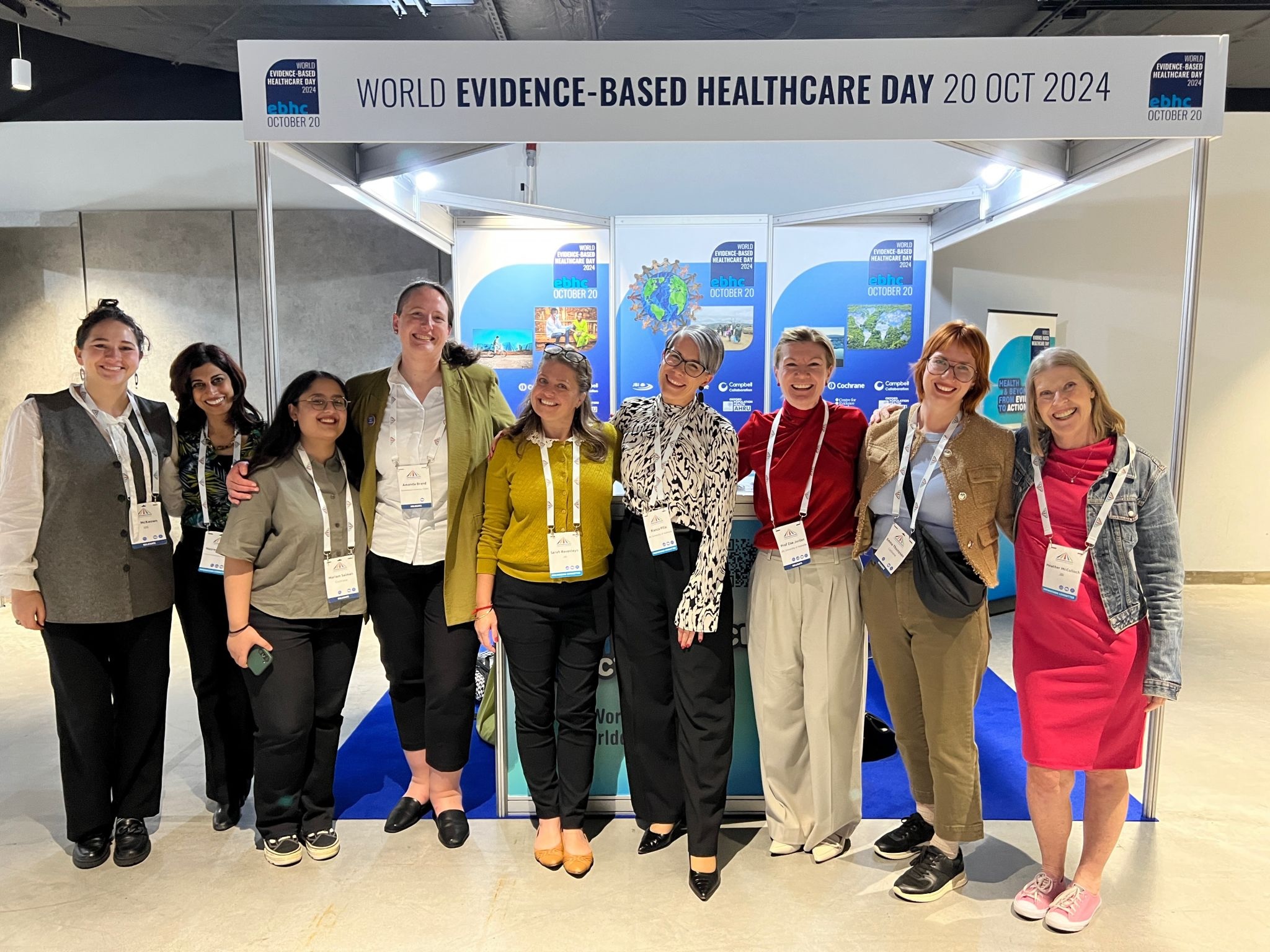 World EBHC Day steering committee and comms committee standing in a line to face camera at the World EBHC Day exhibition booth