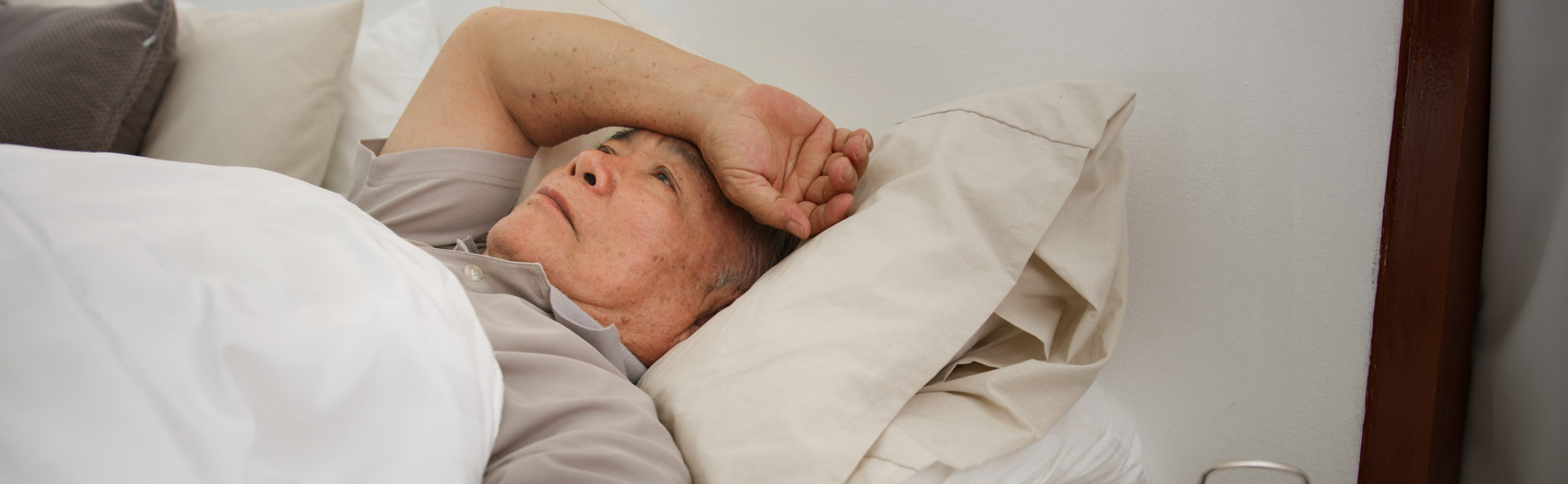 Older man lays in bed looking tired and contemplating an oral appliance for his sleep apneoa