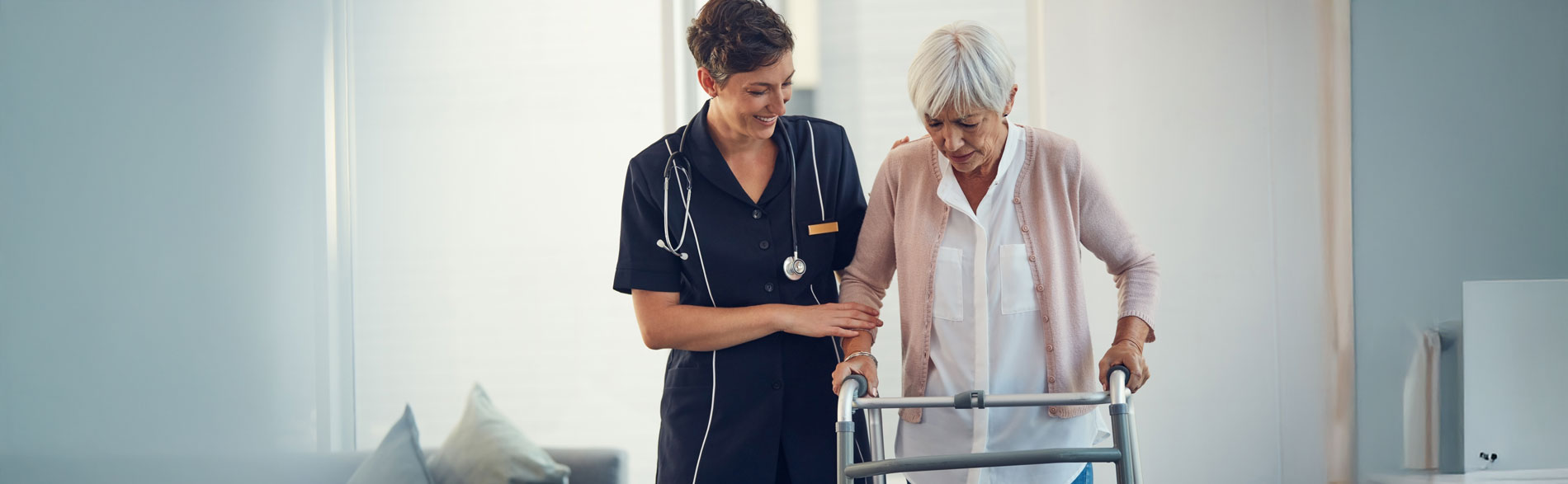 A clinician assists an older person to walk with a frame