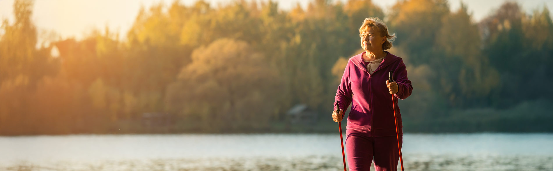 An older woman walks next to a lake, using physical activity to modulate her endogenous pain