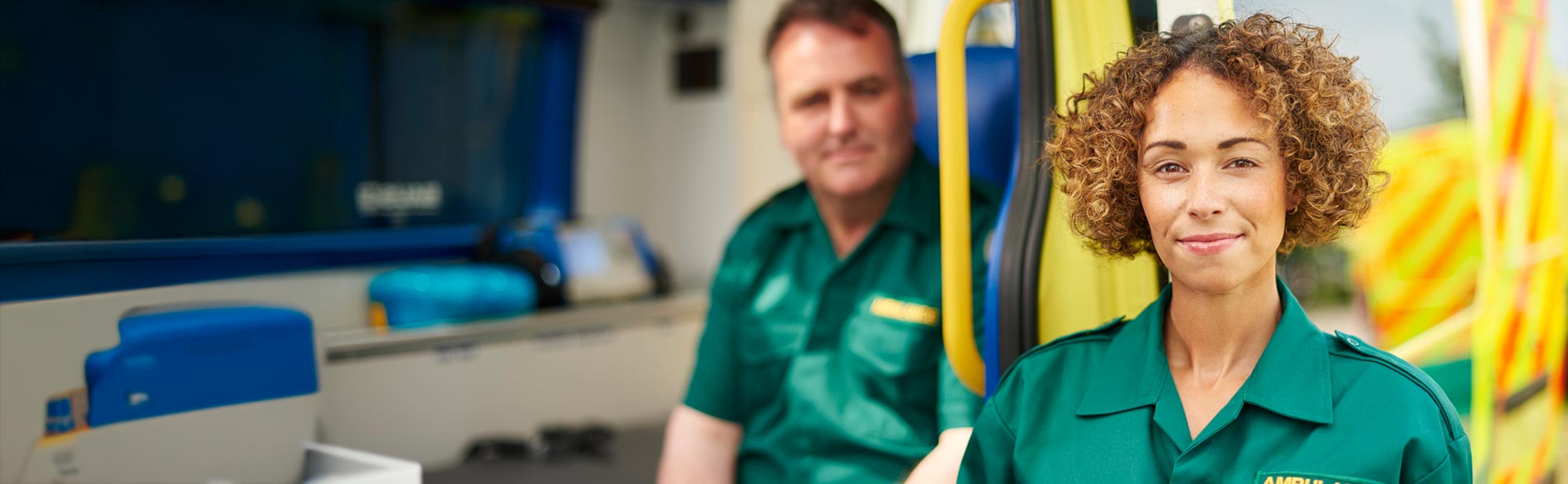 Two paramedics inside and next to an ambulance.