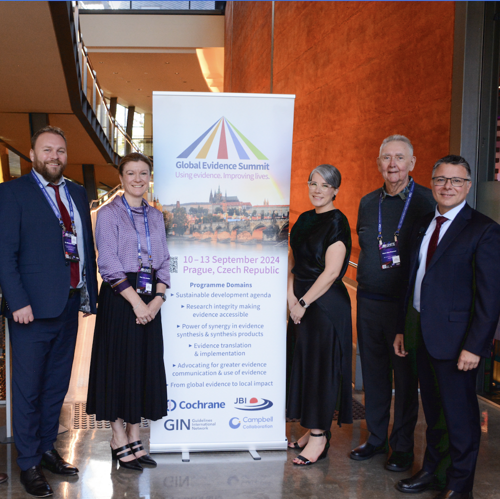 Global Evidence Summit 2024 team poses for group photo at GES 2024 banner