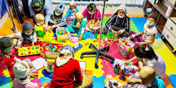 Ill children playing together on a colorful floor mat.