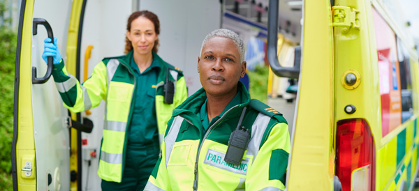 Two paramedics stand in the back doors of an ambulance