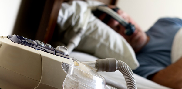 Man laying in bed while connected to a CPAP machine