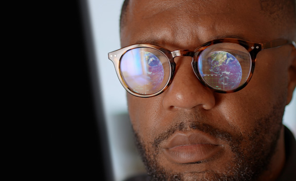 Closeup of a mans face with geographic search filters reflected in his glasses