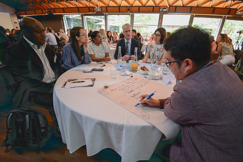 Group work around tables  showing one group in the foreground with a note taker using texta and butchers paper