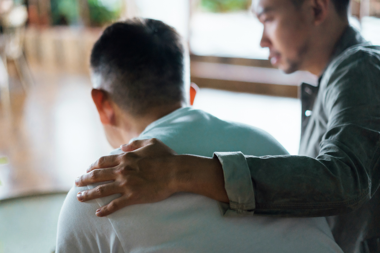 Relative offers comfort to another by placing a hand on their shoulder