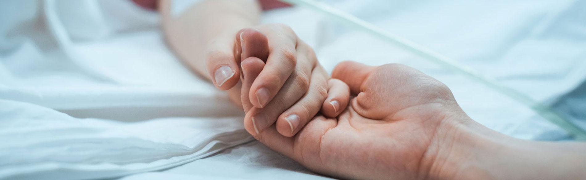 Close up of adult holding sick childs hand.